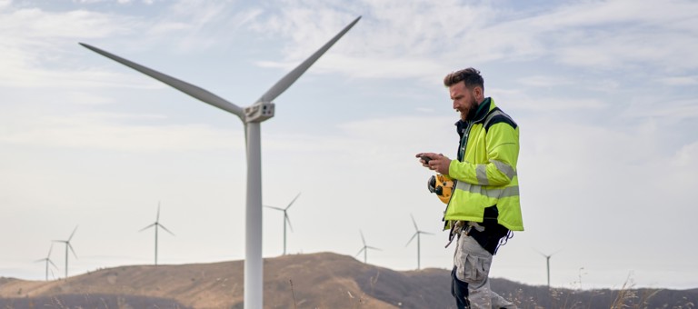 A man looking at his phone at a windfarm