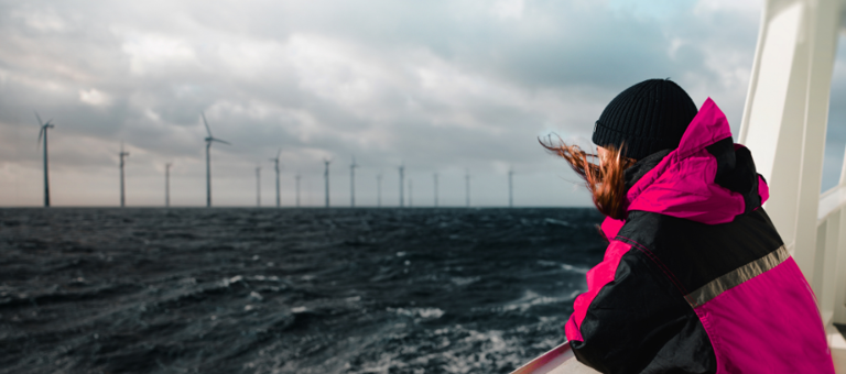 Woman on a boat looking at an offshore wind farm