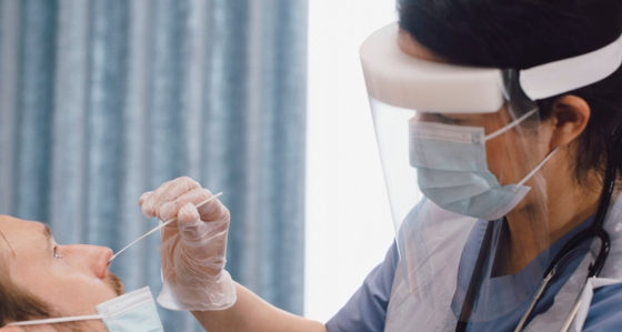 A woman wearing PPE taking nasal swab from a patient