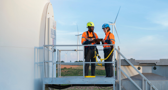 Two workers inspecting a wind turbine