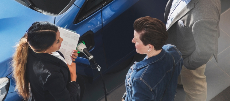 People having a conversation next to an electric car