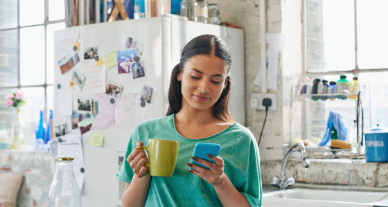 A woman in a kitchen looking at her phone