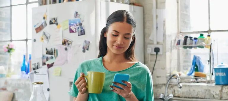 A woman in a kitchen looking at her phone