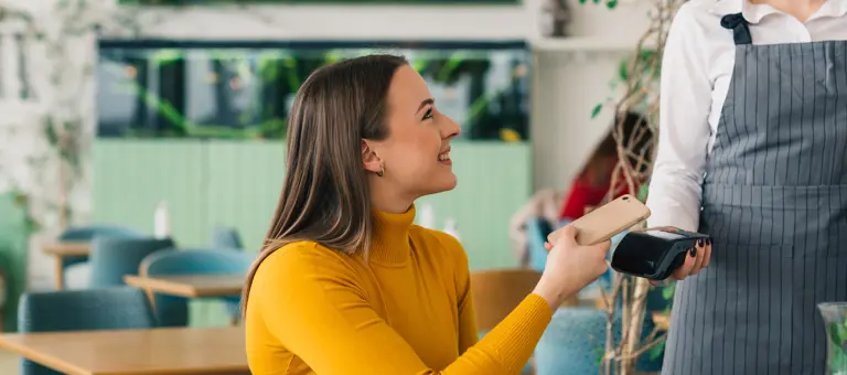 Woman in coffee shop paying with phone