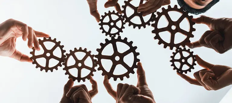 Group of people holding cogs together