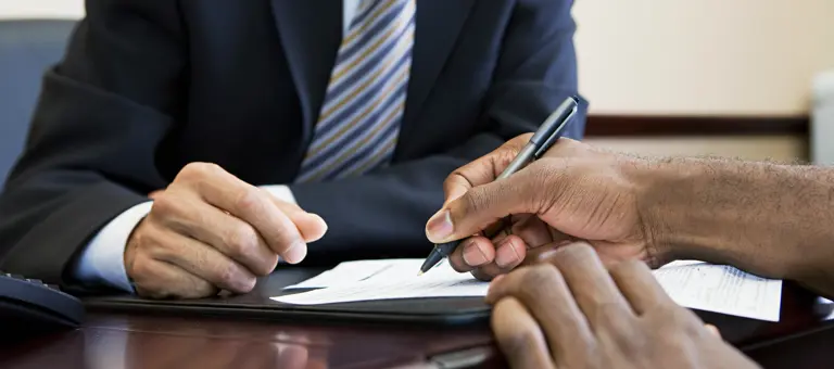 A hand holding a pen signing a document