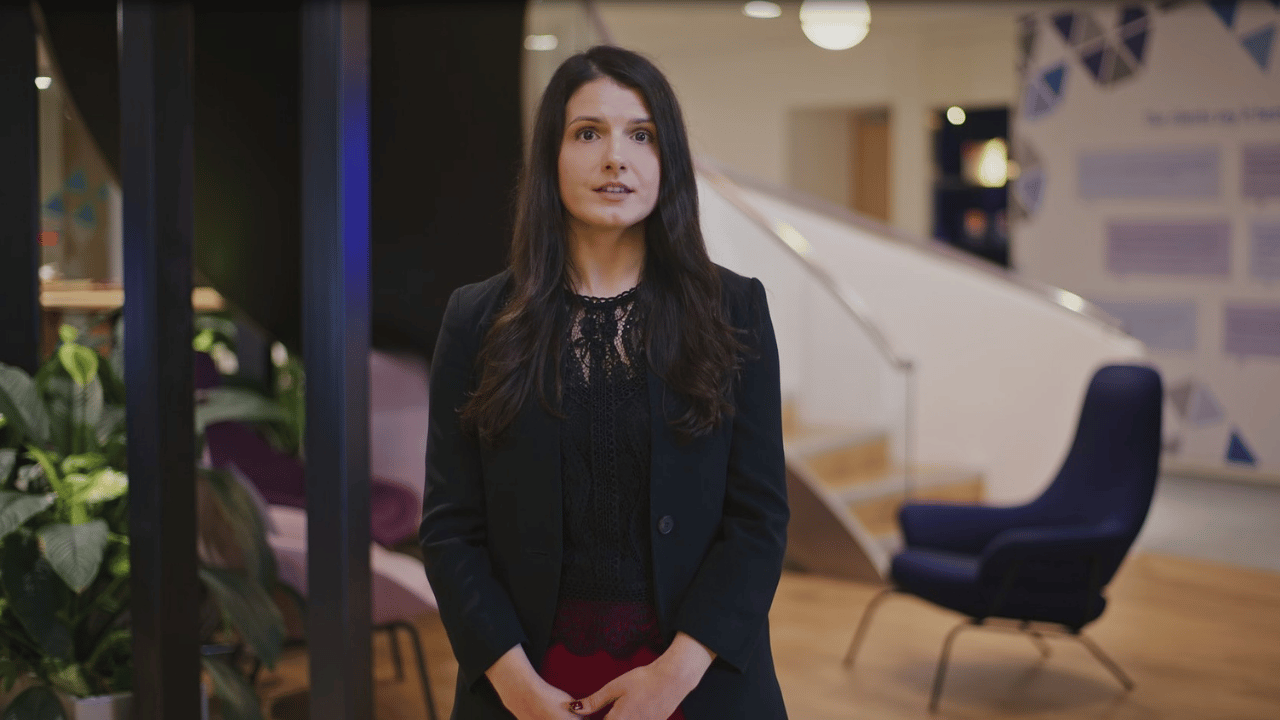 Woman dressed in black standing in a modern office environment facing the camera