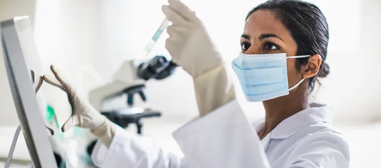 A lab technician looking at a sample in a test tube