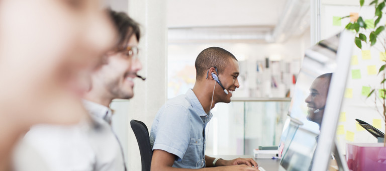 Smiling people wearing headsets working in a call center