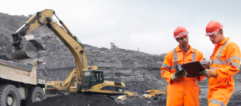 Two mine workers looking at a clipboard