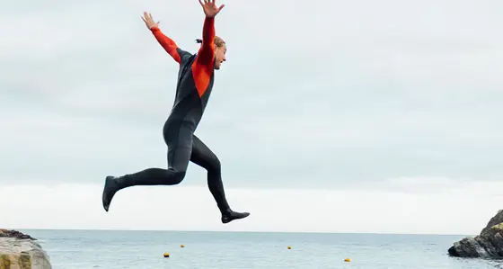 A person jumping from a harbour wall into the sea