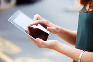 A woman holding a tablet and pressing the screen