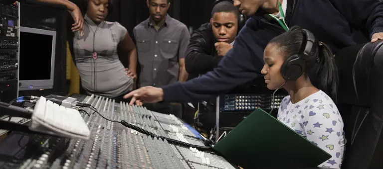 A woman sitting at a recording studio mixing desk