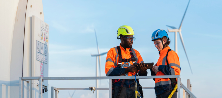 Two workers inspecting a wind turbine