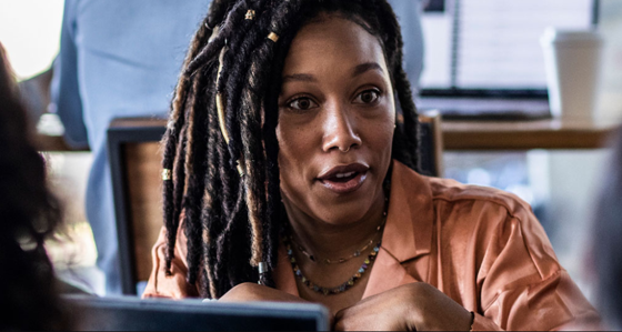A black woman with her hair in braids in conversation
