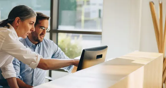 A man and woman in discussion looking at a laptop