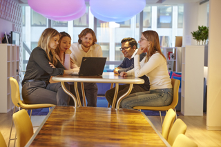 Five colleagues looking at a laptop in a relaxed working environment