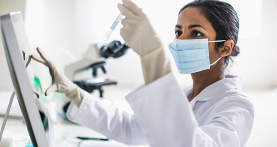 A lab technician looking at a sample in a test tube