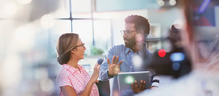 Two colleagues talking in front of a laptop in an office setting
