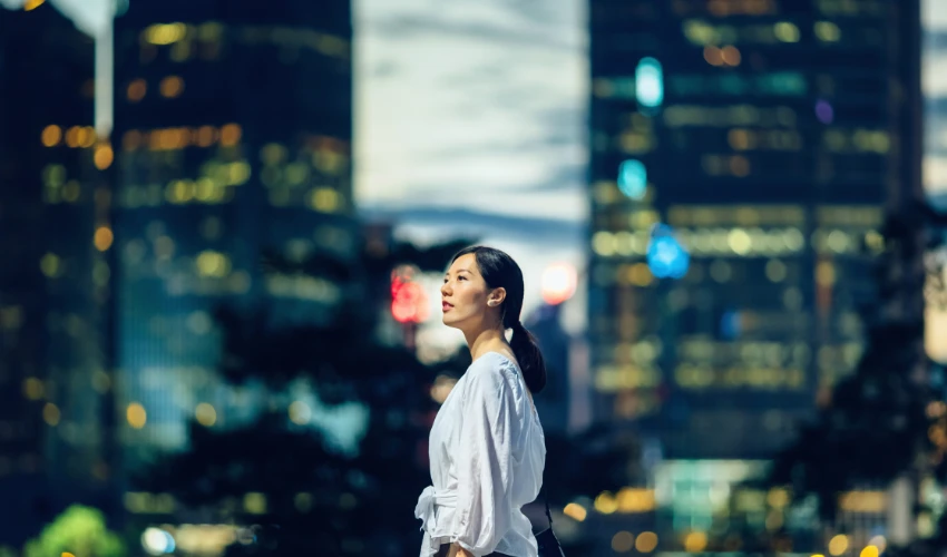 A young woman looking towards the sky in busy nighttime cityscape