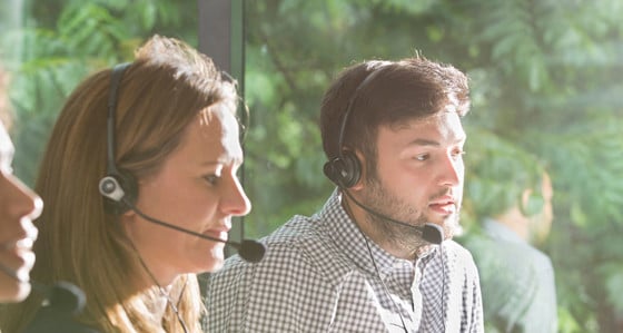 Three people wearing headsets working in a call centre