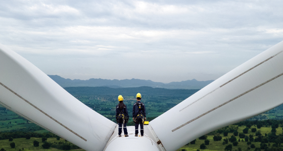 Two engineers standing at the top of a wind turbine