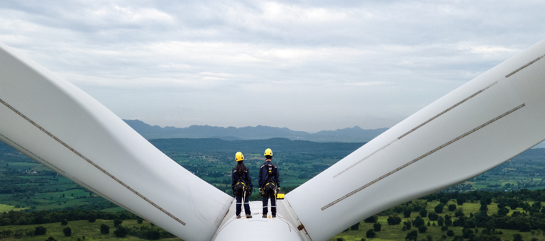 Two engineers standing at the top of a wind turbine