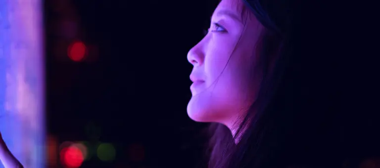 Young asian woman using touch screen in financial district at night