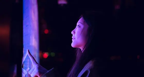 Young asian woman using touch screen in financial district at night