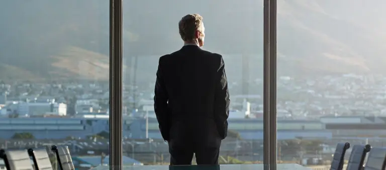Man in boardroom looking out the window to a landscape view
