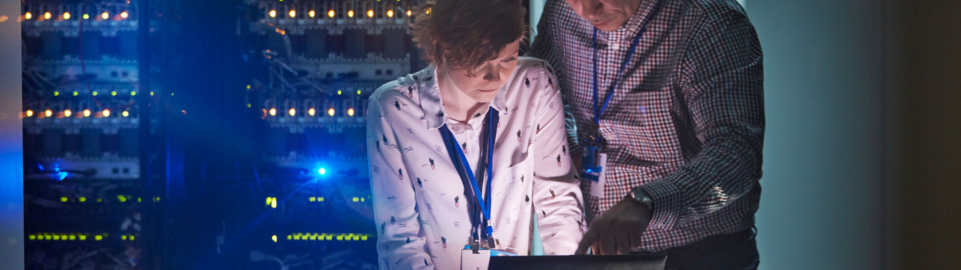 A man and a woman in a data centre looking at a laptop