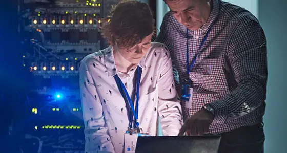 A man and a woman in a data centre looking at a laptop