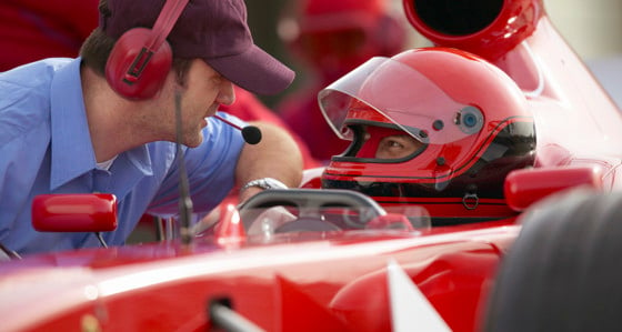 Racing driver talking with a man wearing a headset during a pit stop 