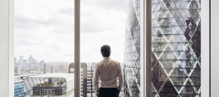 Businessman looking out window at London's financial district