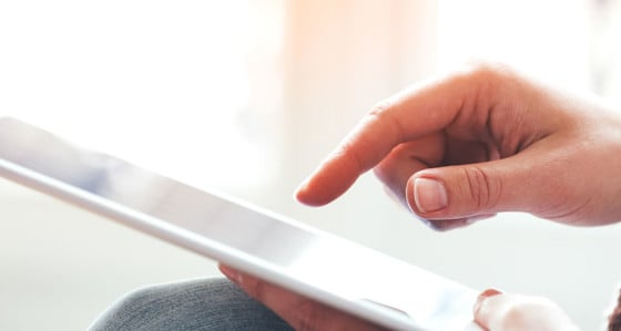 A hand with finger pointing to a tablet