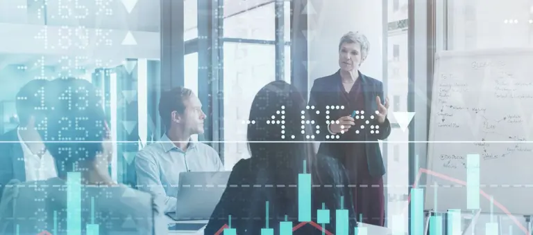 Businesspeople meeting in the boardroom superimposed over a graph showing the ups and downs of the stock market
