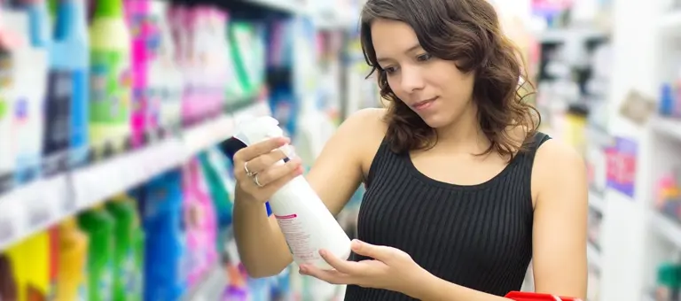A woman looking at a cleaning bottle in a supermarket