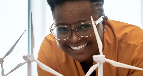 A smiling woman looking at model miniature wind turbines 
