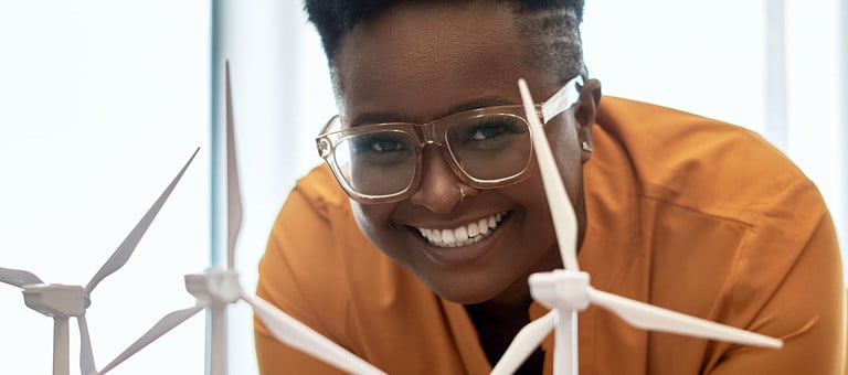 A smiling woman looking at model miniature wind turbines 