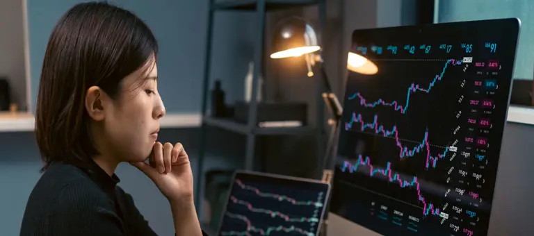 A woman looking at graphs on multiple screens