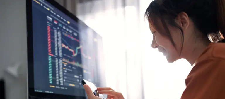 Woman using her smartphone in front of a computer