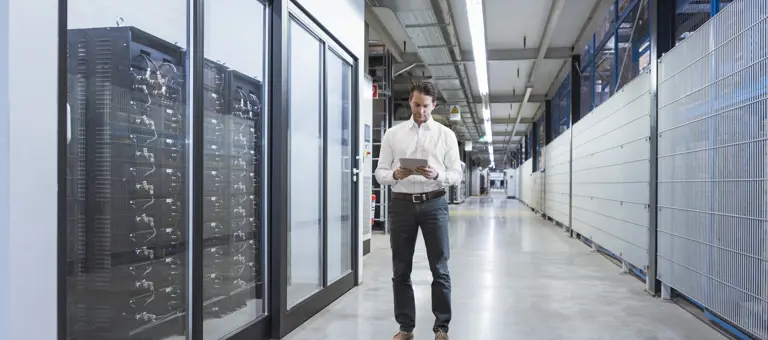 Man on tablet next to a server room