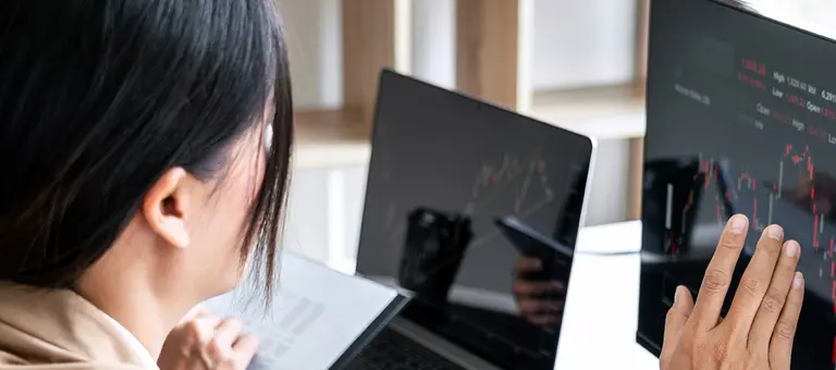 A woman touching a screen displaying stocks index prices