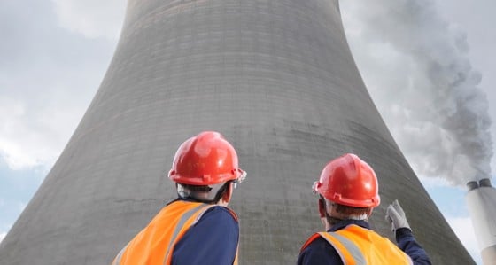 Two men in hard hats staring upwards at a cooling tower