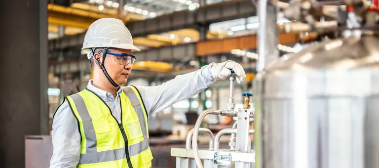 Asian worker operating a gas tank in a factory