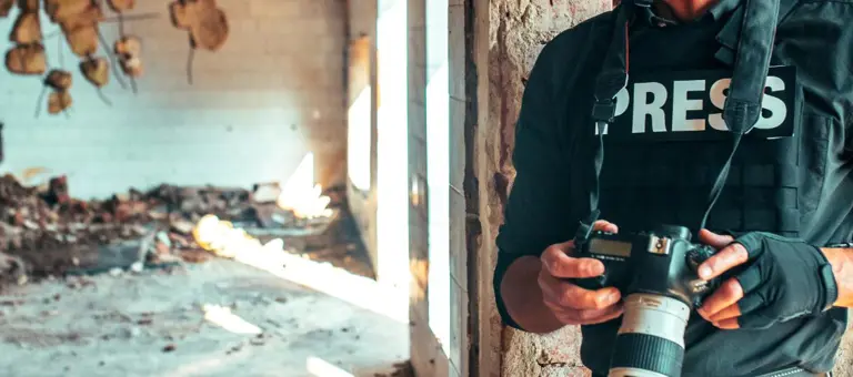 Man in press uniform taking photos in conflict