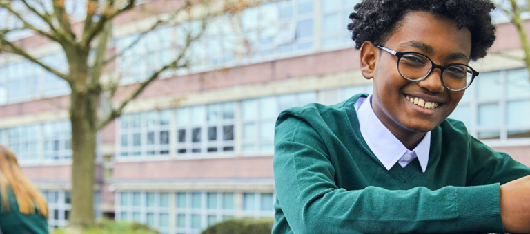 Child at school smiling while holding a smartphone