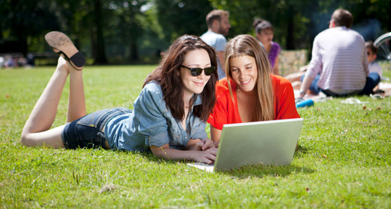 Two friends outside looking at a laptop