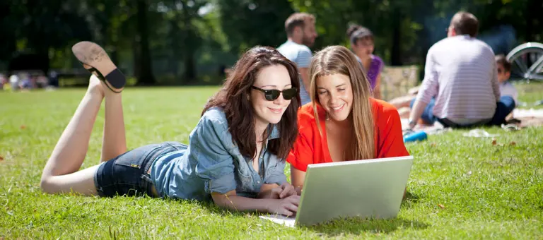 Two friends outside looking at a laptop