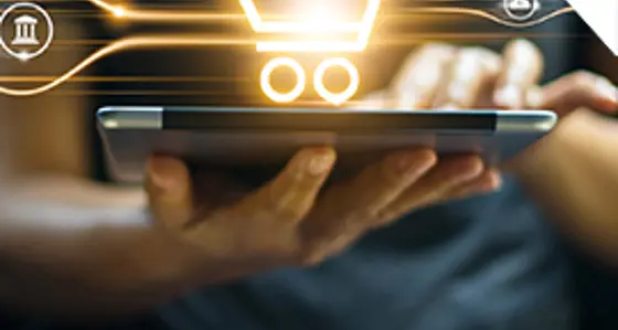 A hand holding a tablet with a shopping trolley symbol above it